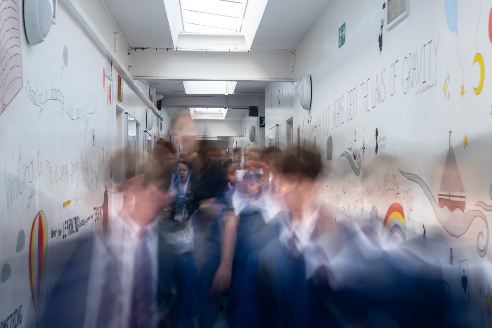 Creative motion-blurred shot of pupils walking through a school corridor with mural artwork